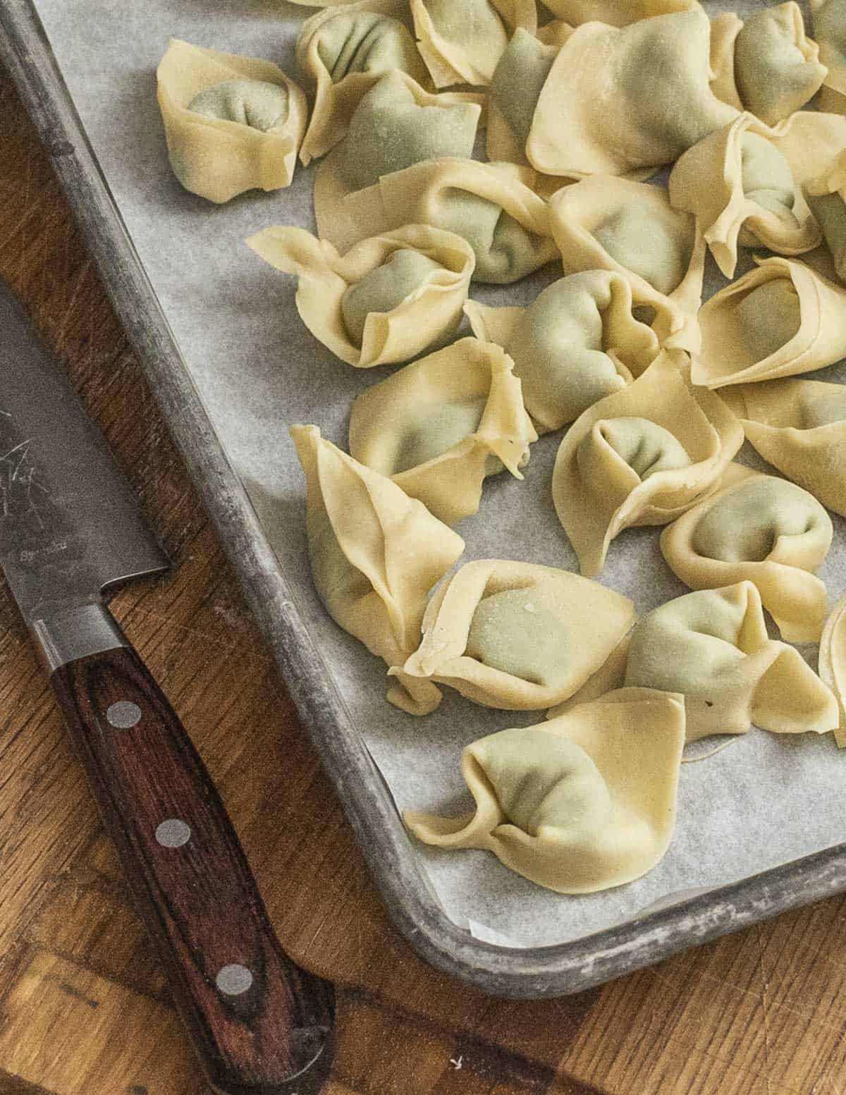 Fresh pansotti pasta on a baking sheet. 