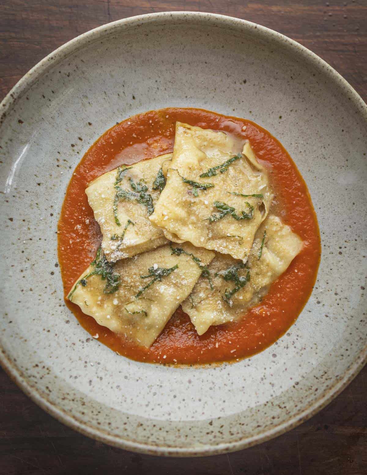 Ravioli marinara on a plate garnished with parmesan cheese. 