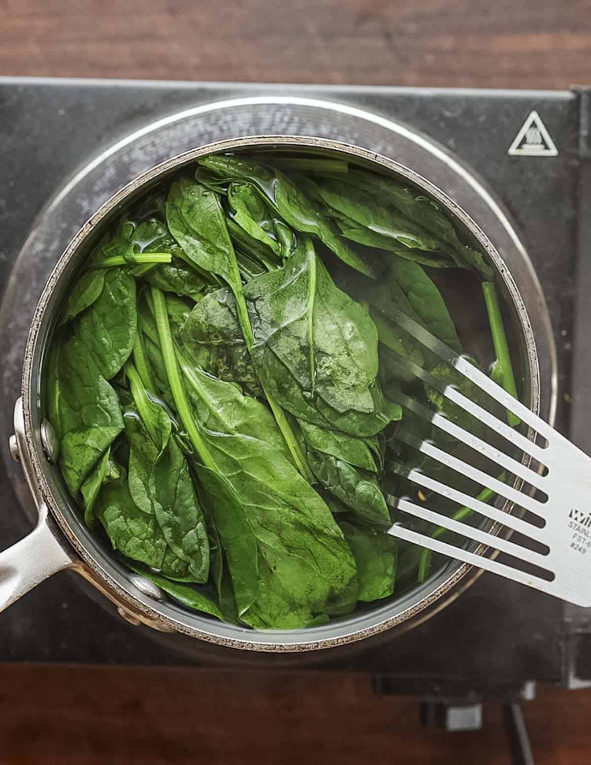 Blanching spinach in a pot of boiling water. 