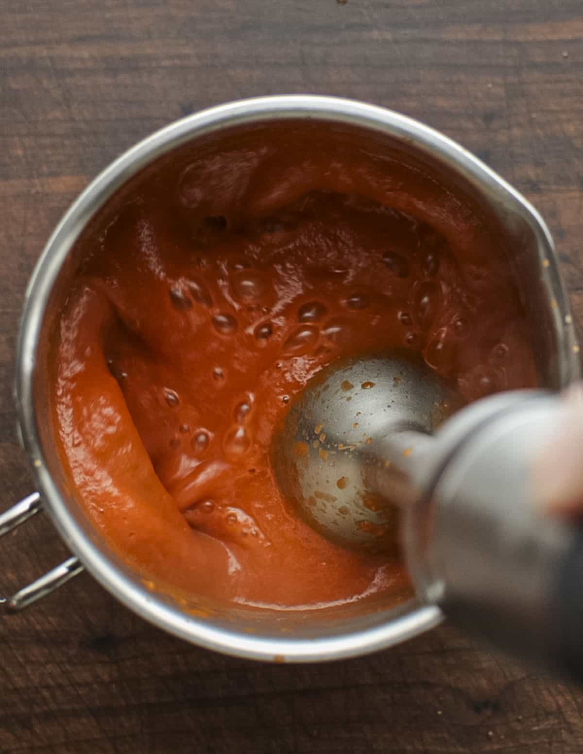 Pureeing fresh marinara sauce with a hand blender. 