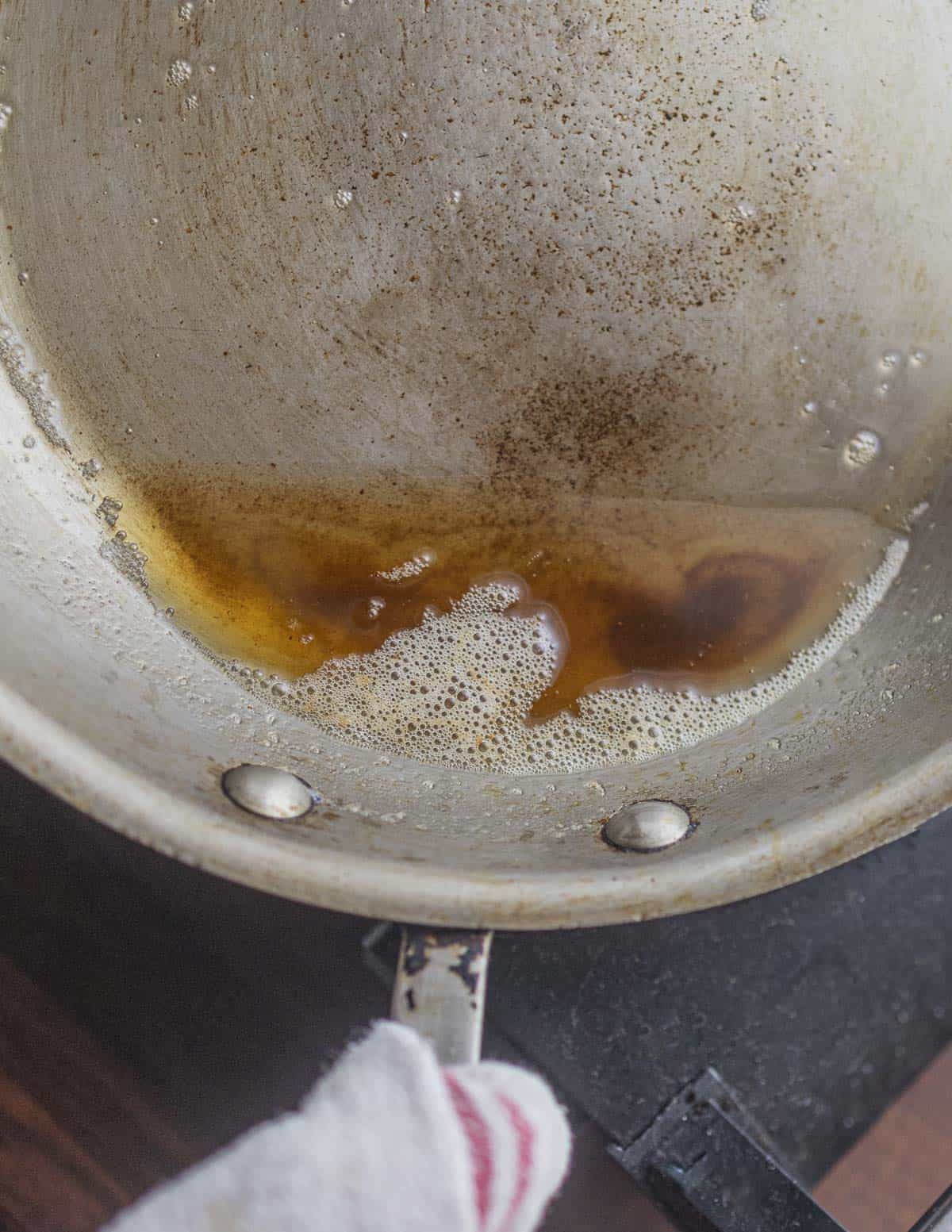 A pan tilted to show the exact stage of perfect brown butter before adding wine to the pan. 