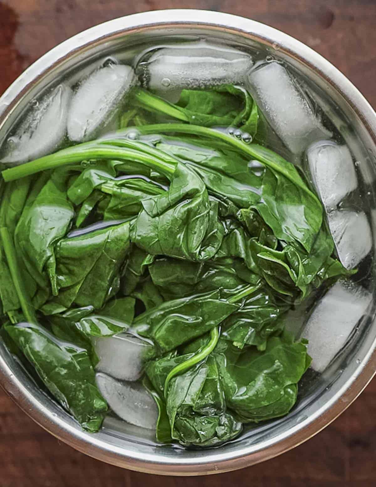 Chilling blanched spinach in an ice bath. 