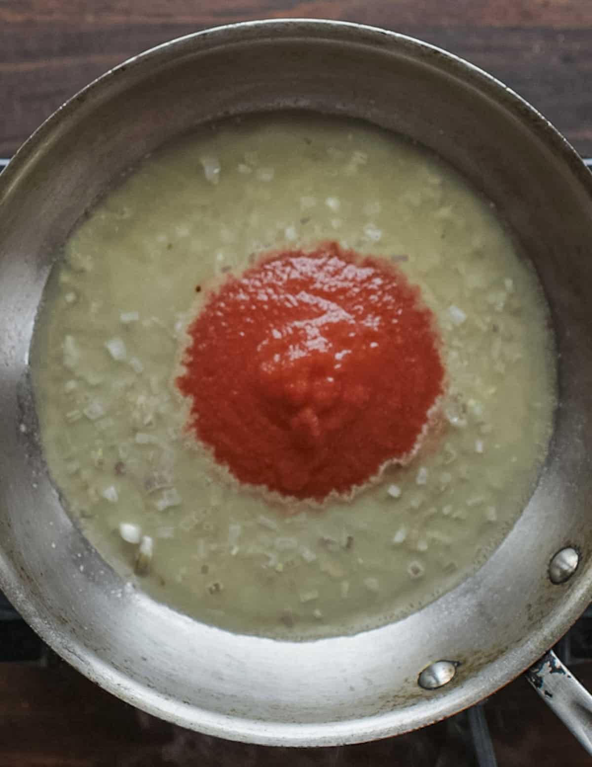 Adding tomato sauce to a pan of beer and shallots. 