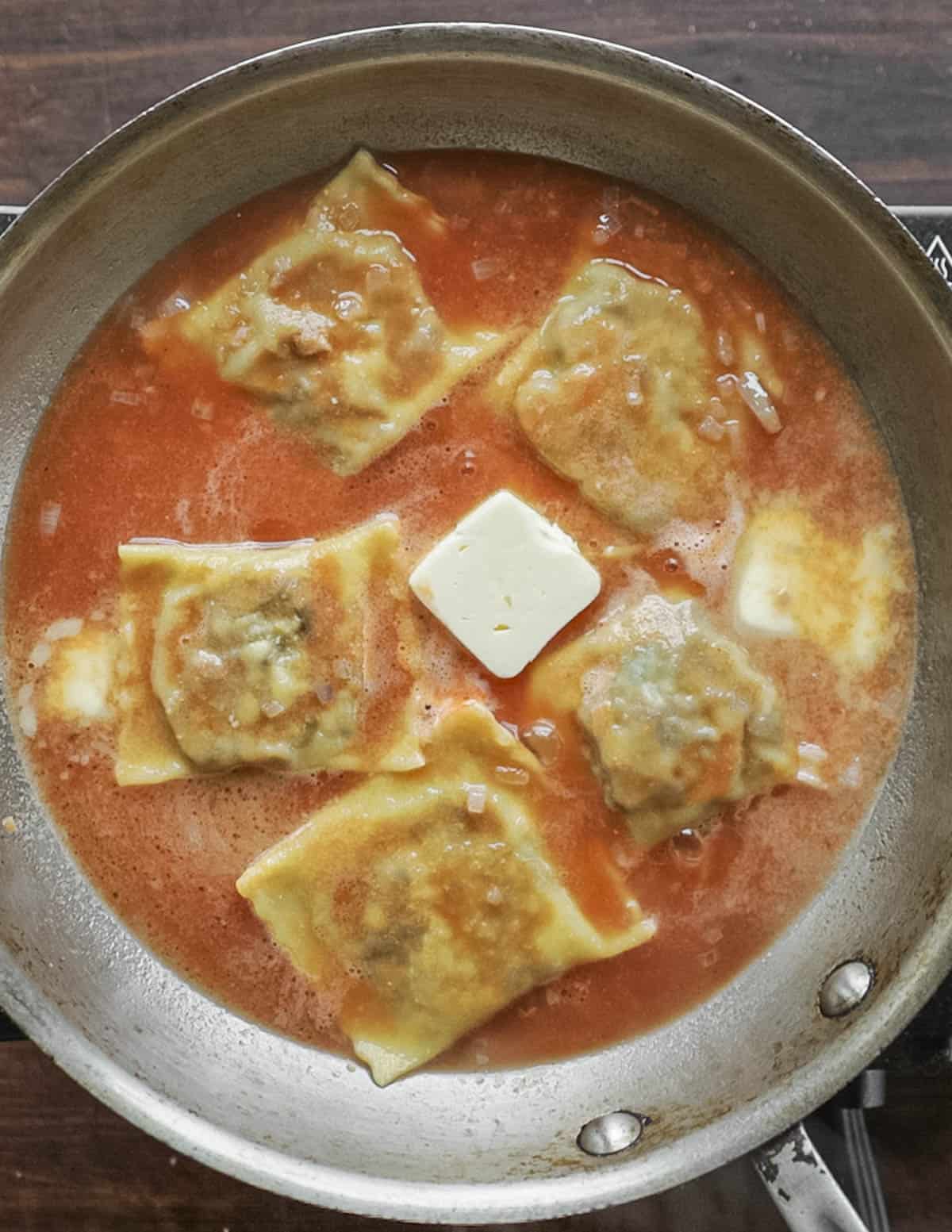 Adding cold diced butter to make a tomato-beer butter sauce for ravioli. 