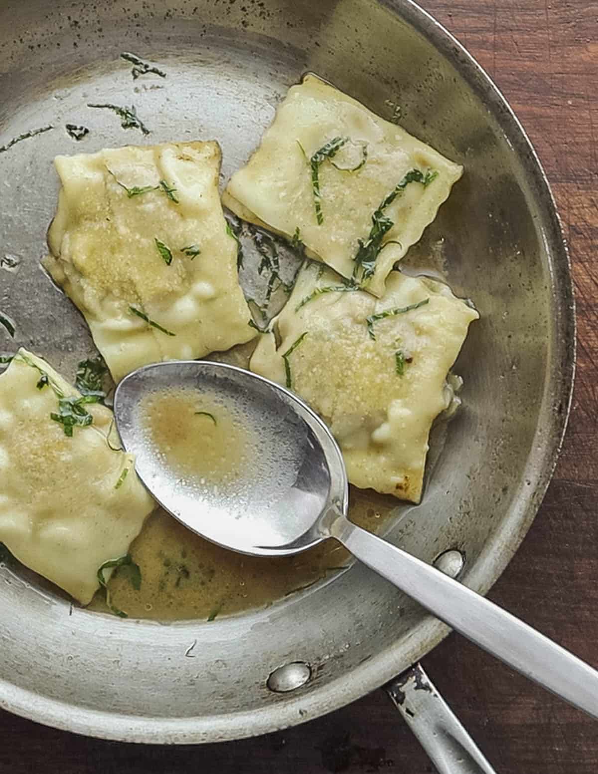 Ravioli in a pan with brown butter sage sauce. 