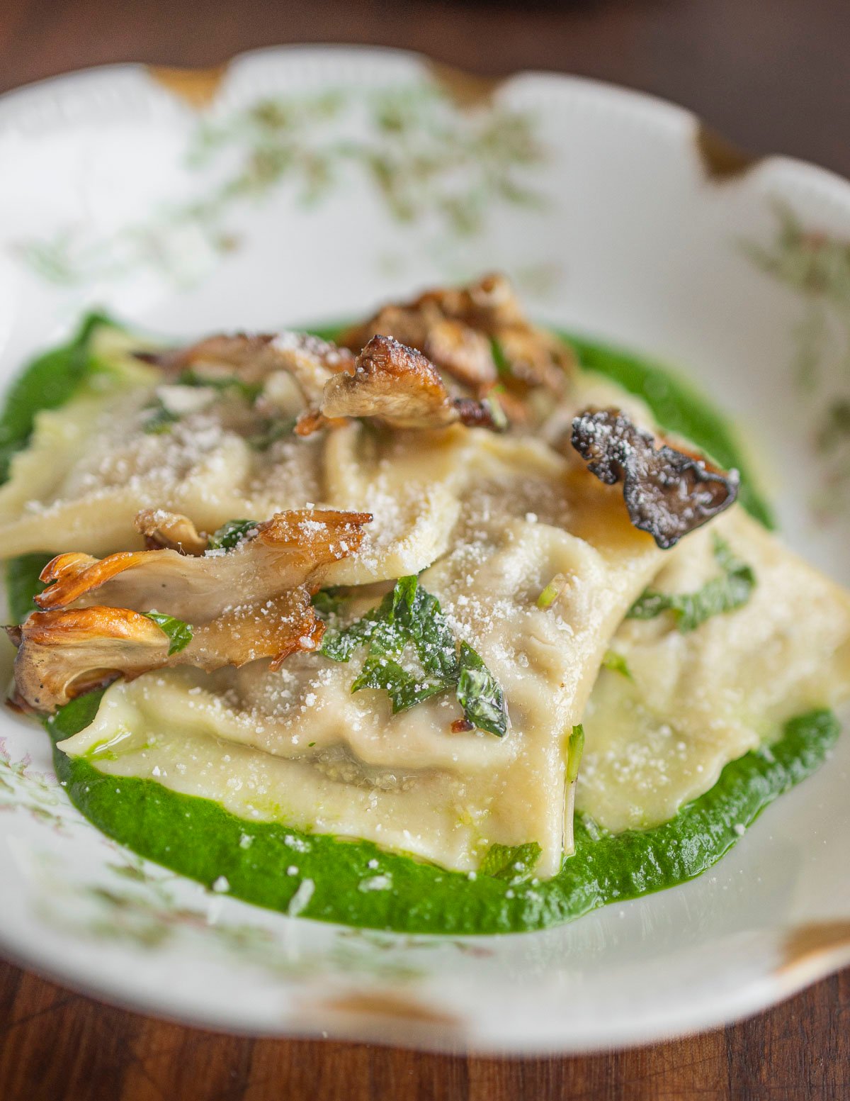 Porcini ravioli served with a spinach puree and sauteed mushrooms. 