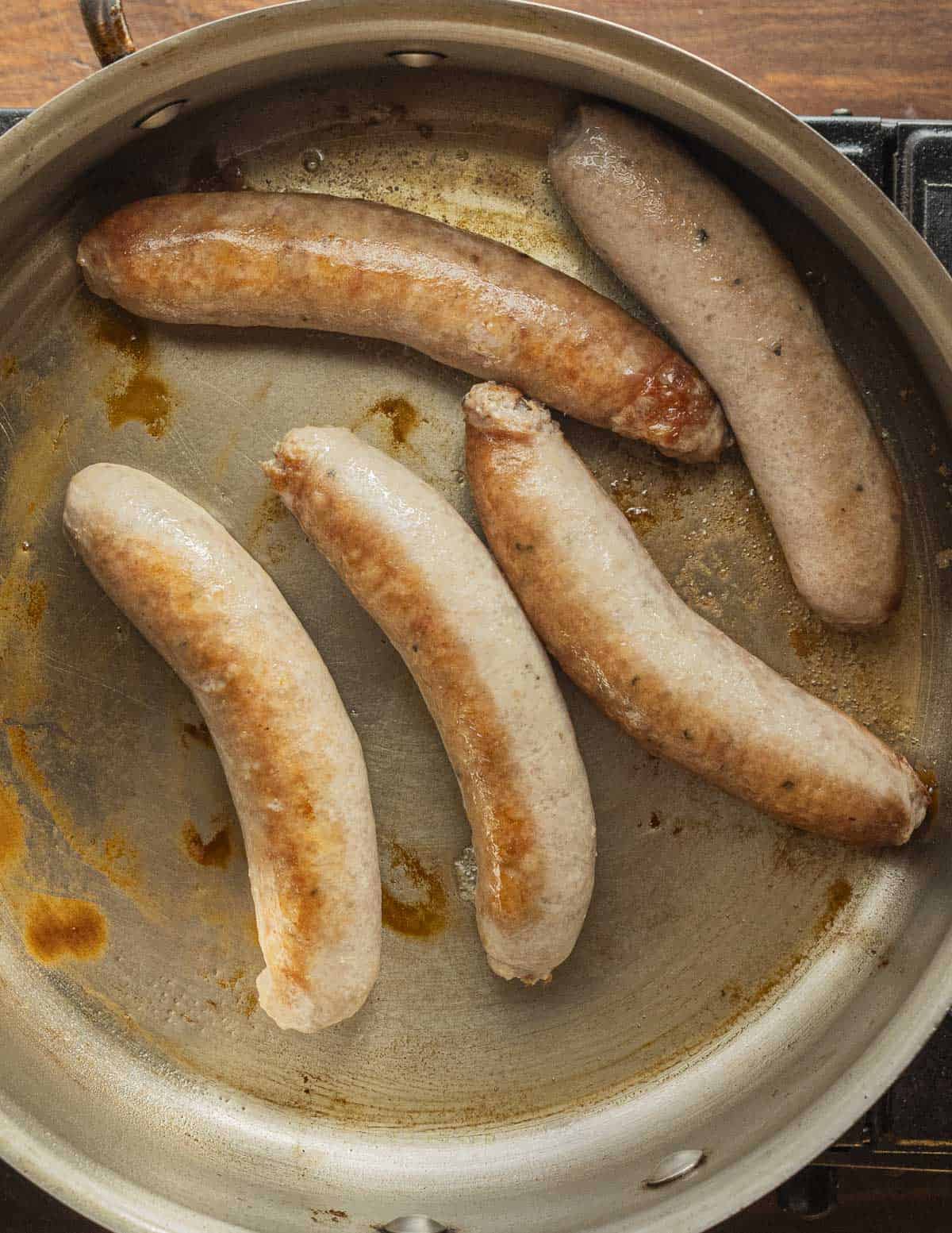 Browning sausages in a pan. 