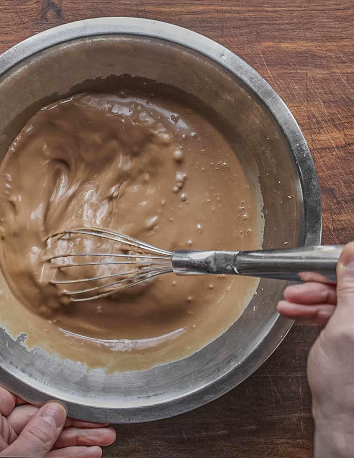 Beating cocoa cream and eggs in a bowl with a whisk. 