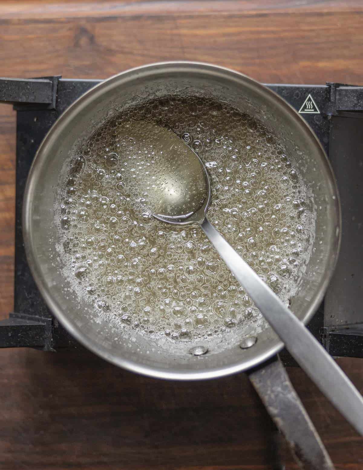 Heating water and sugar in a pan to make caramel. 