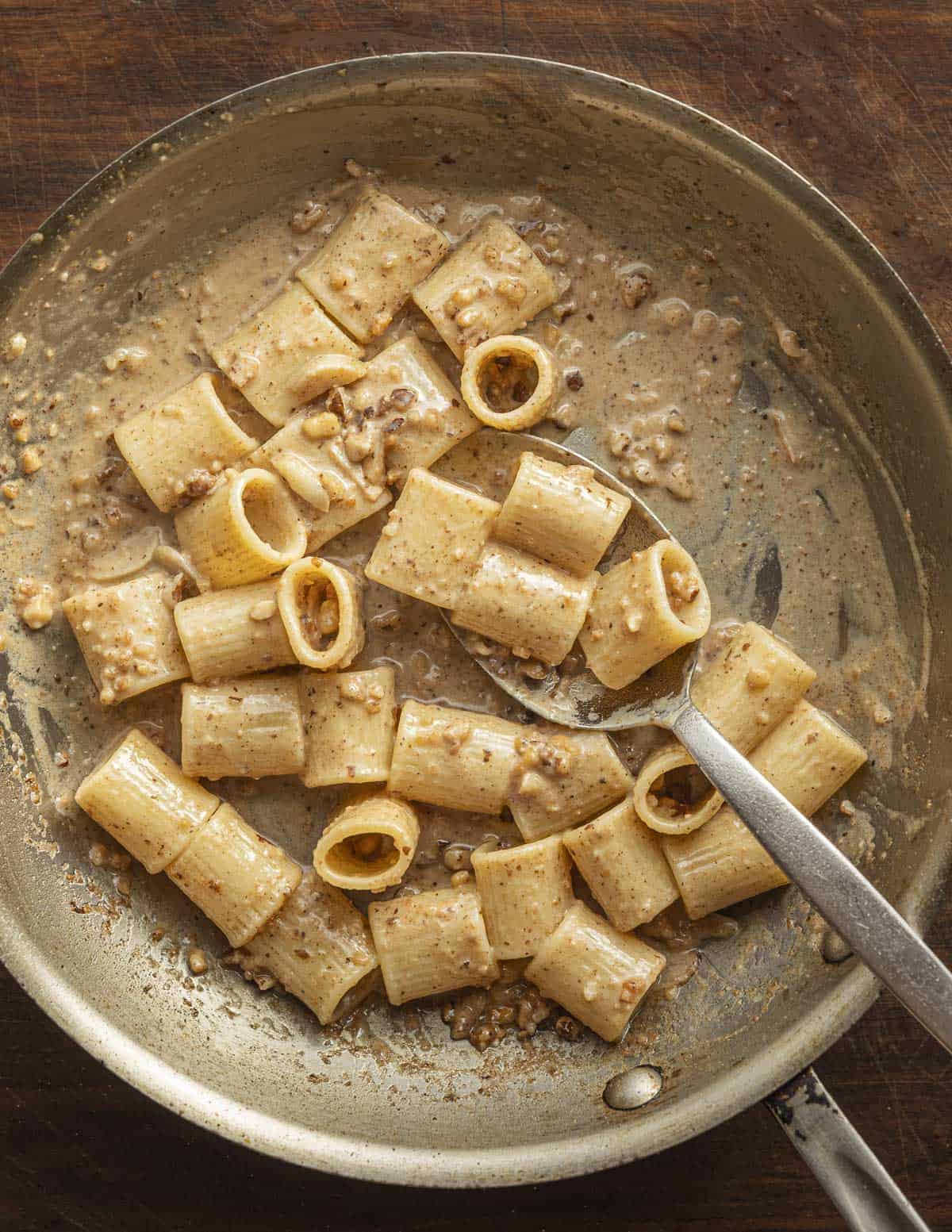 A finished pan of mezze maniche pasta with walnut sauce showing the perfect consistency and that the pan is nearly dry.