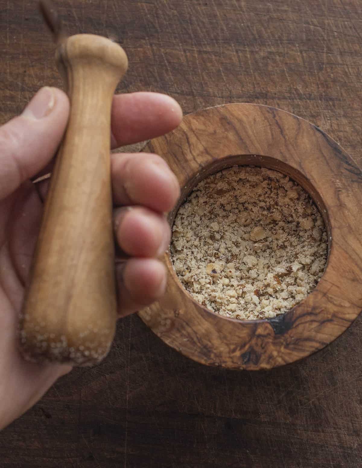 Crushing walnuts with an olive wood mortar and pestle. 