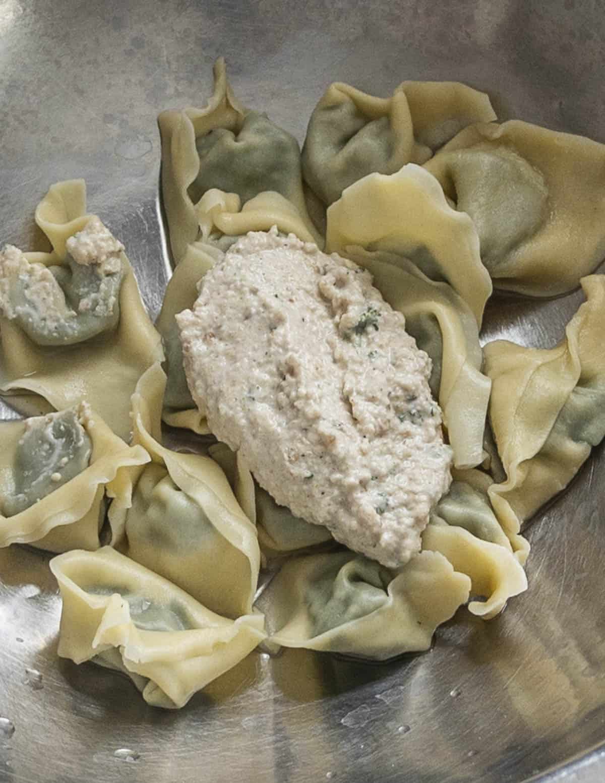 Tossing filled pansotti pasta with walnut sauce. 