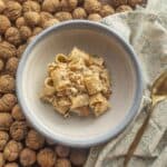 Mezze maniche pasta with Italian walnut sauce served in a bowl garnished wtih parmigiano cheese and walnuts.