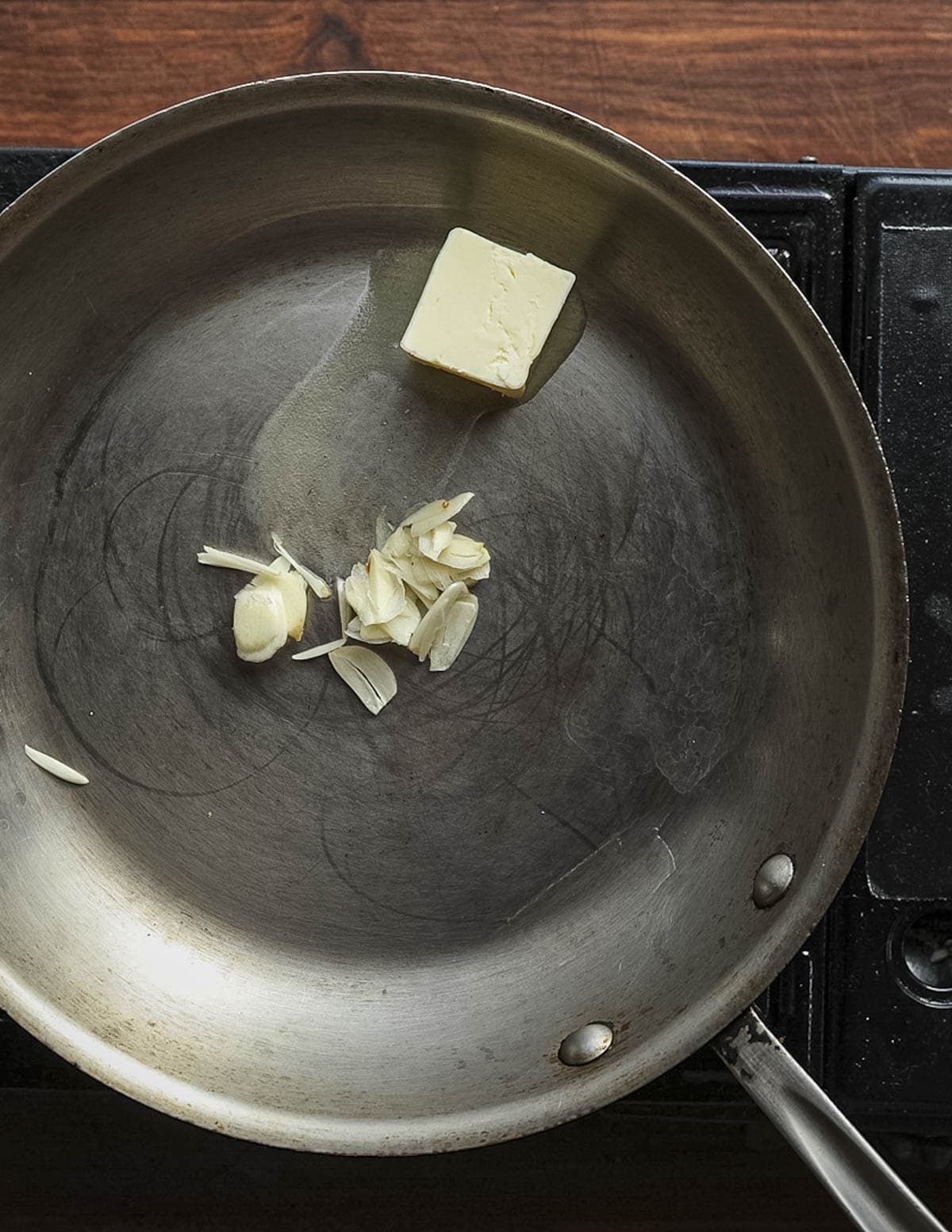 Melting butter in a stainless steel saute pan with garlic.