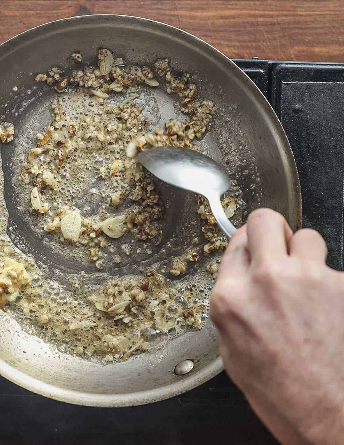 Stirring a pan of ground walnut and garlic cooking in butter.