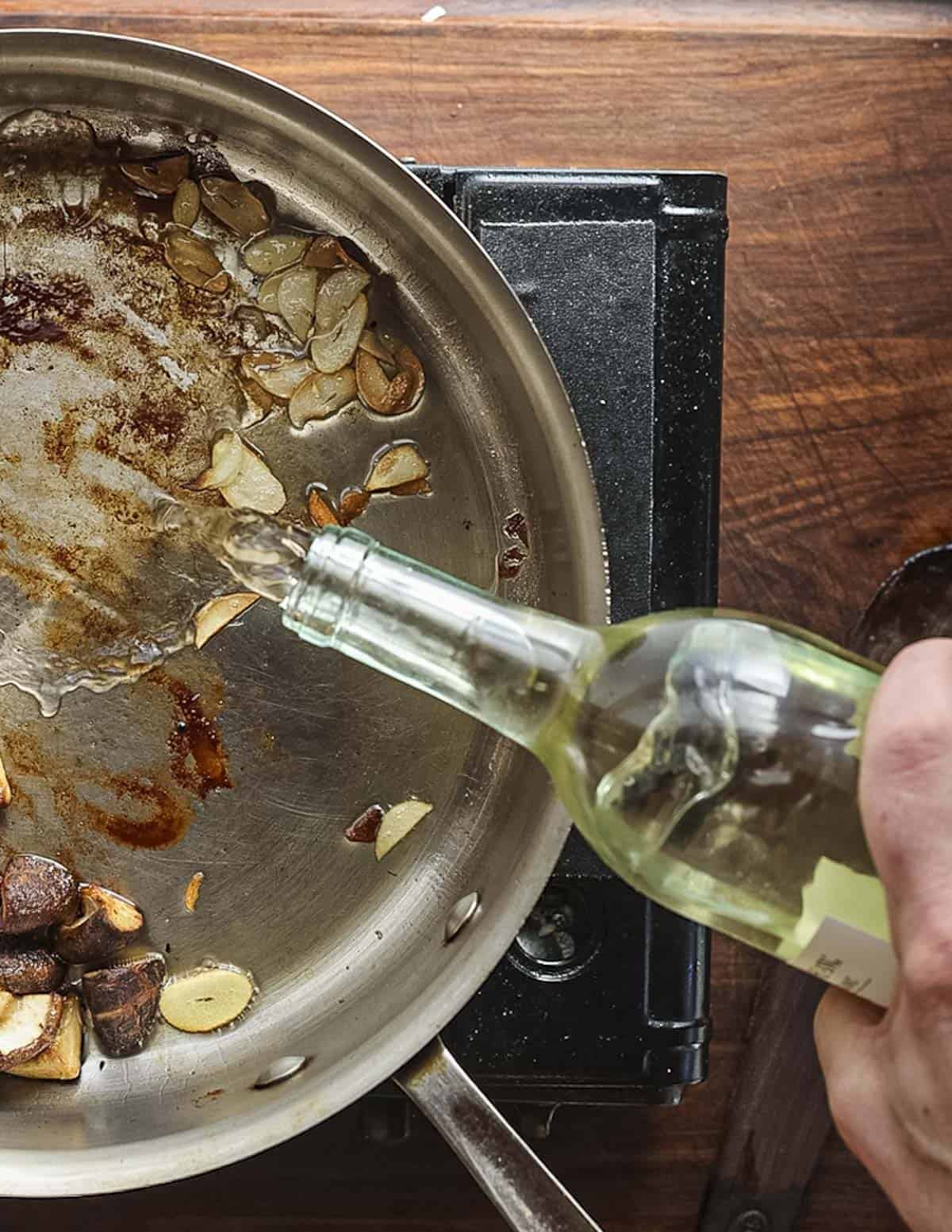 Deglazing a pan of garlic and mushrooms with white wine. 