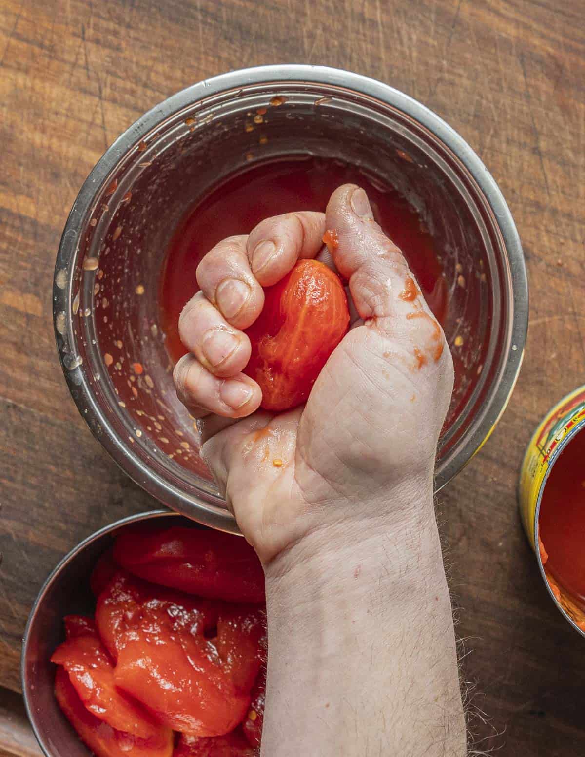 Squeezing seeds from a can of whole peeled tomatoes. 