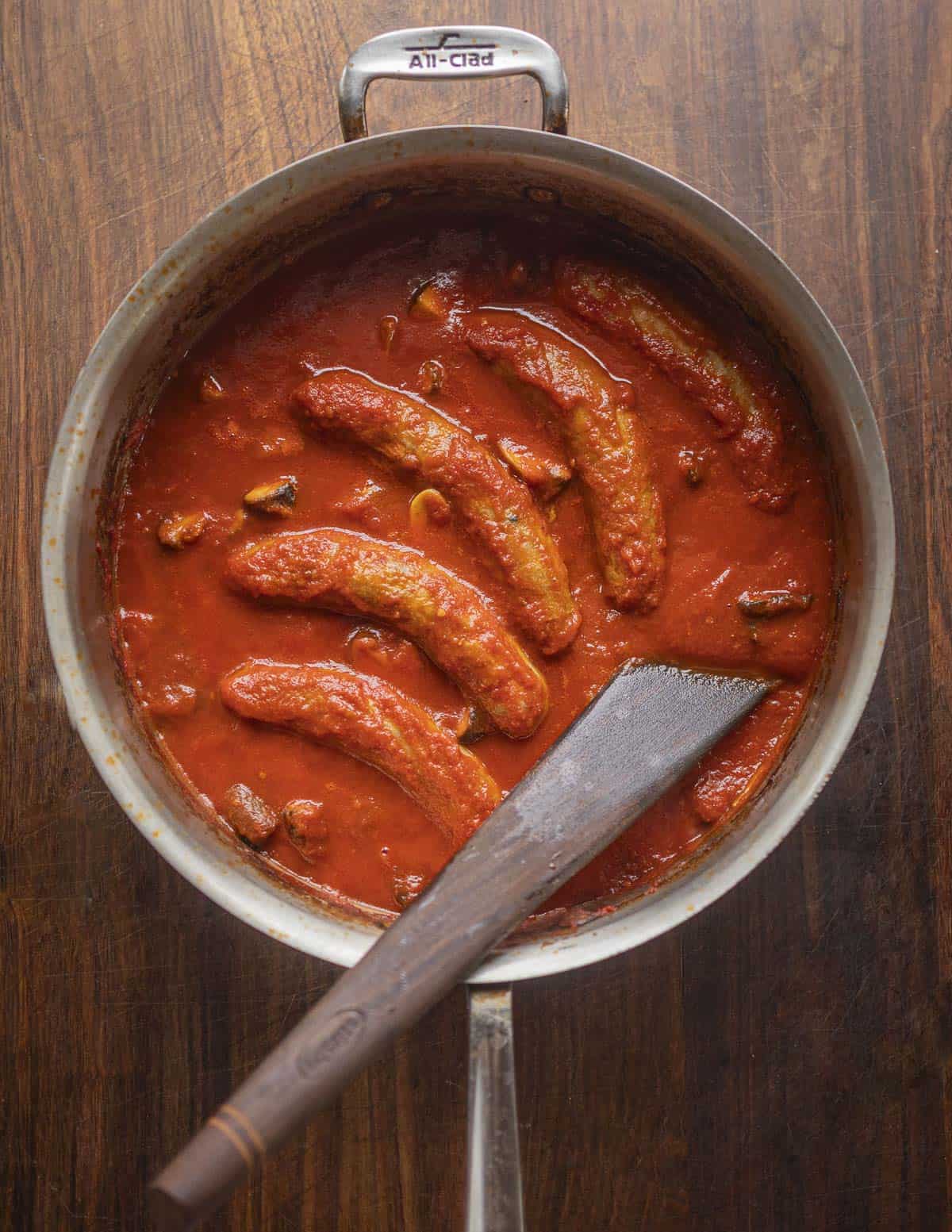 A finished, cooked pan of baked Italian sausage with mushrooms in tomato sauce. 