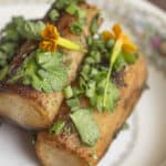 Fried salsify roots on a plate garnished with herbs.