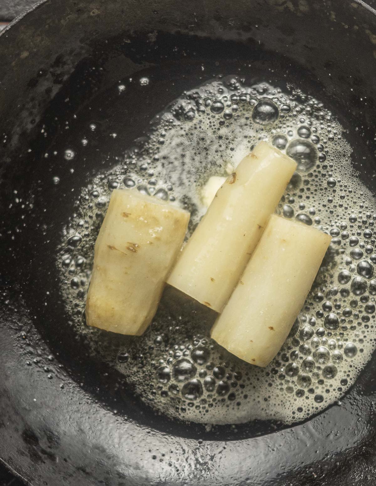 Cooking white salsify roots in a carbon steel pan. 