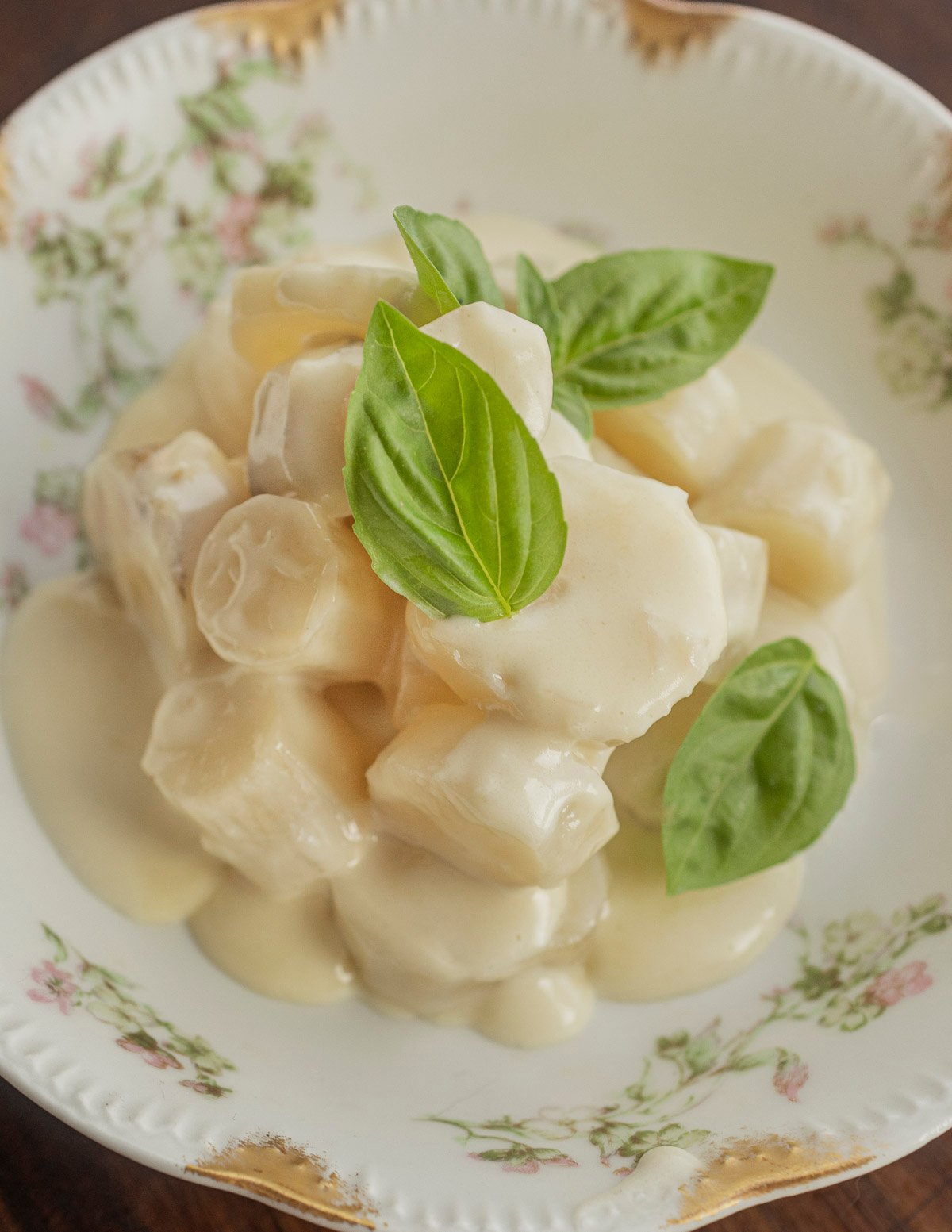 A small bowl of creamed salsify roots garnished with a basil leaf. 