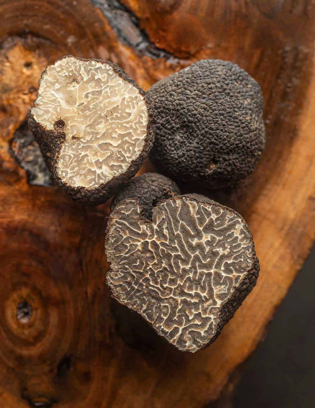 Three grade B truffles cut next to each other showing variation in the color of the inner gleba. 