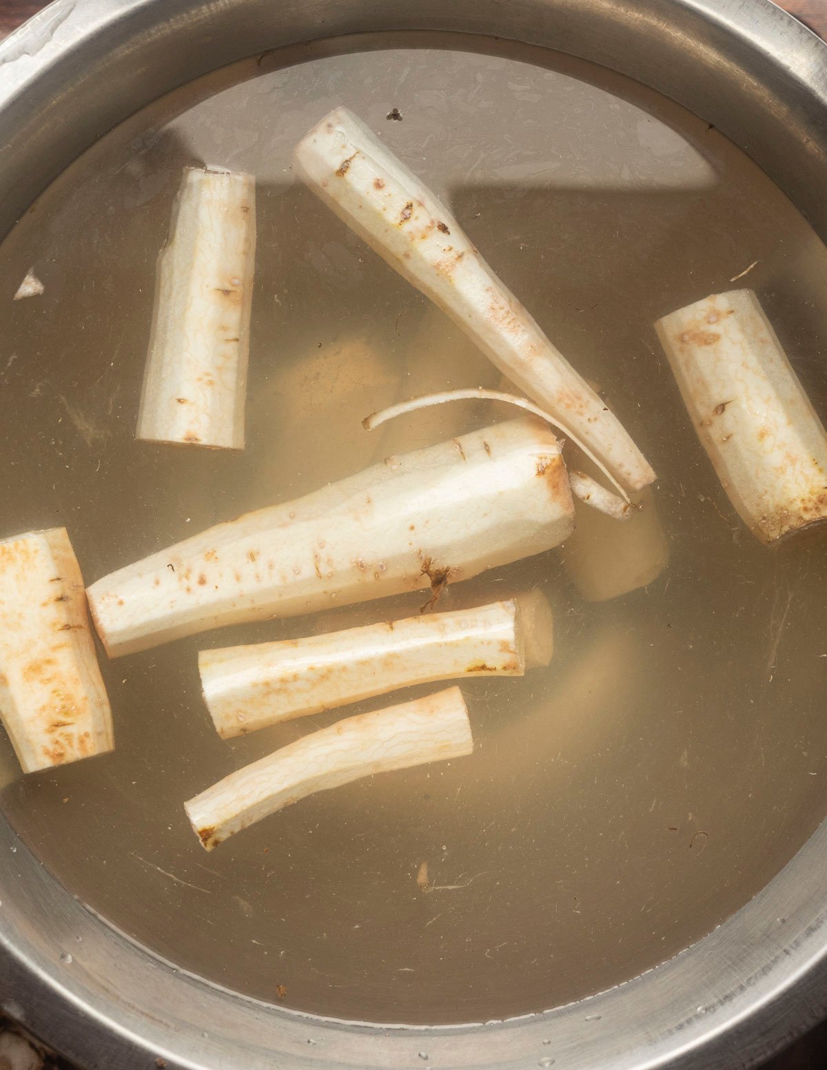 Peeled salsify roots in a bowl of acidulated water to prevent discoloration. 