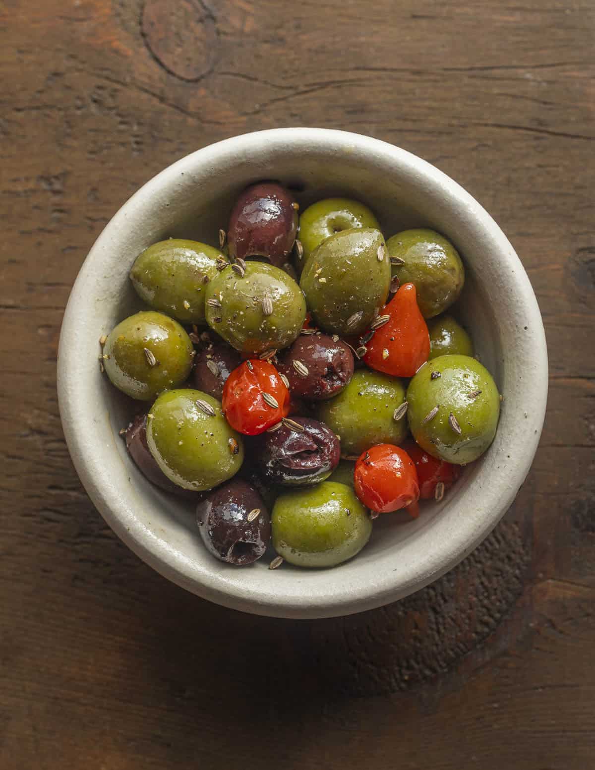 A bowl of castelvetrano olives and kalamata olives with wild fennel seed and boquinho peppers. 