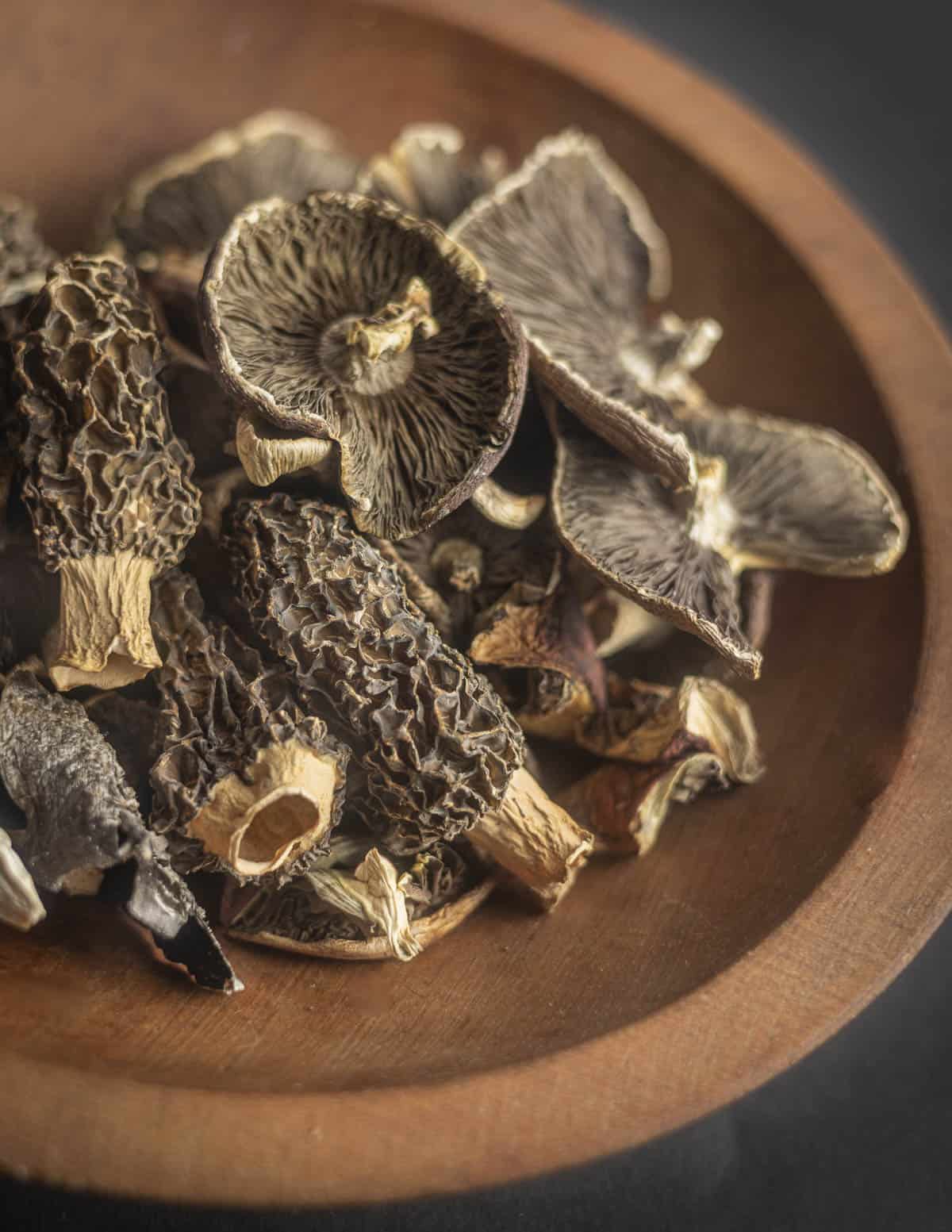 A bowl of dried wild morel mushrooms and wine cap mushrooms. 