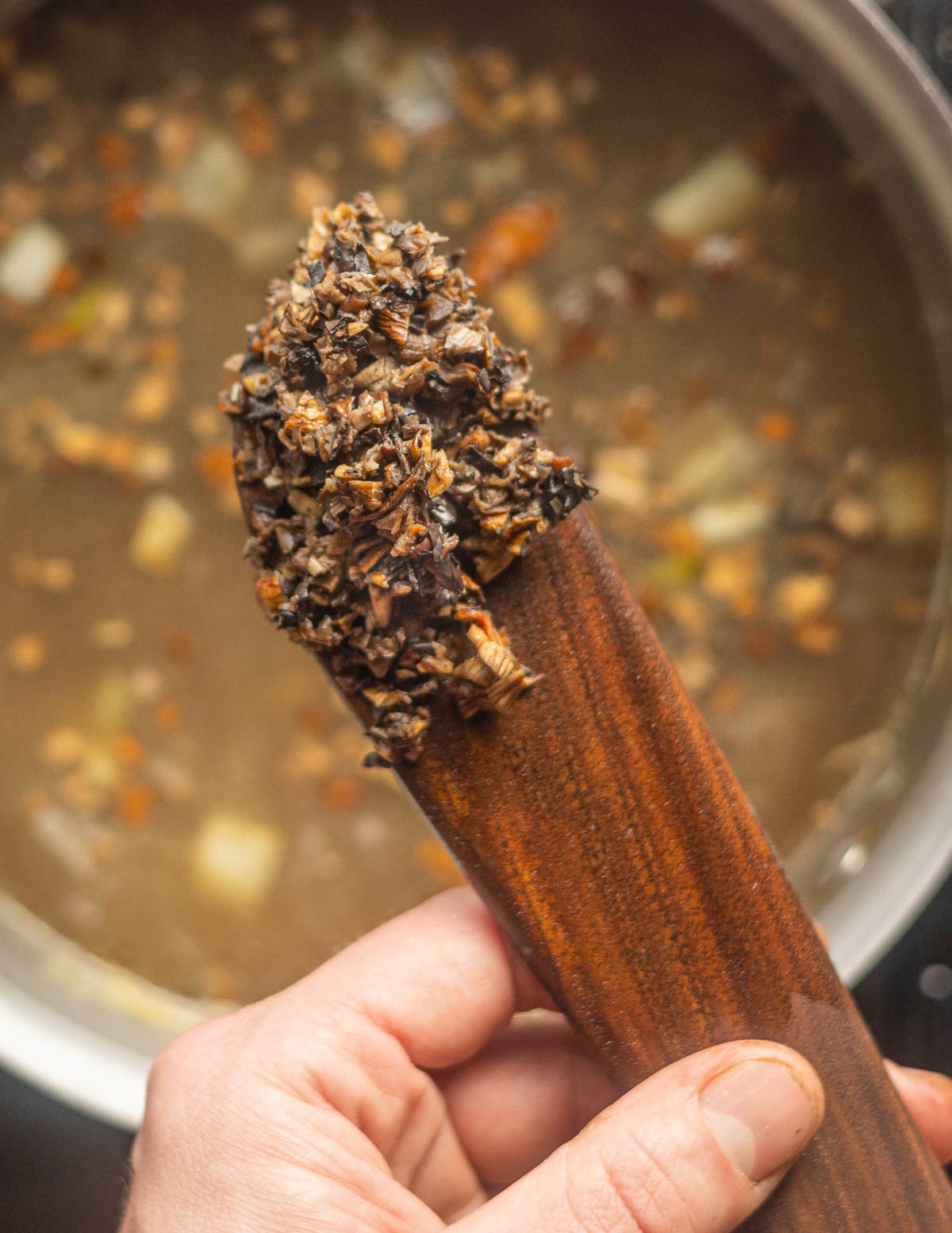 Adding baked dried mushrooms to a pot of soup cooking. 