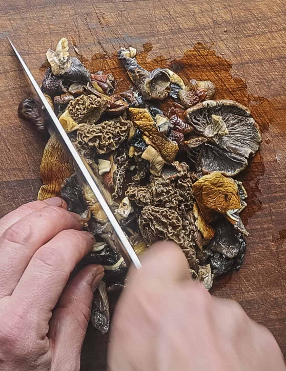 Chopping dried, reconstituted mushrooms with a chefs knife. 
