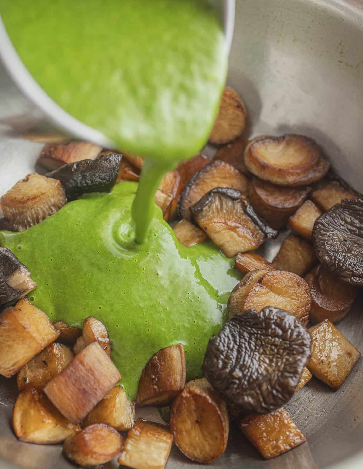 Pouring a green curry sauce into a pan of golden brown caramelized king oyster mushrooms. 