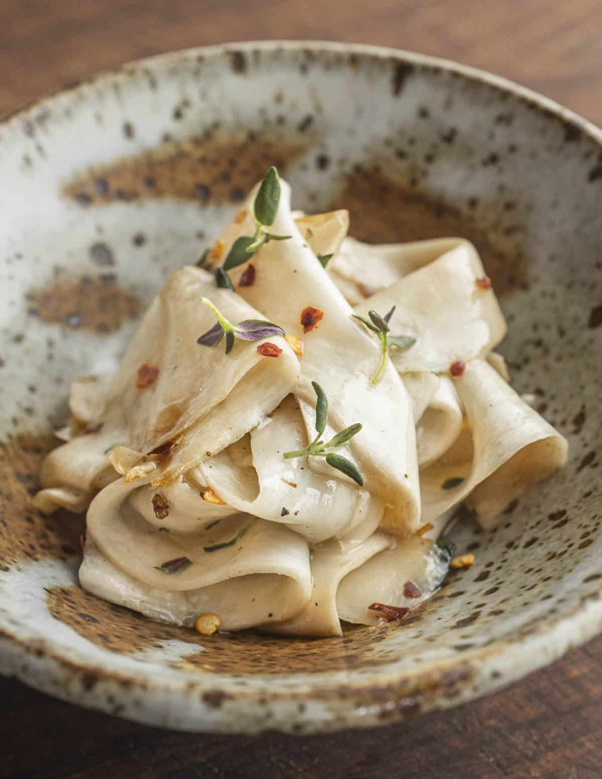 Shaved king oyster mushroom stems with sesame oil, herbs, and chili. 