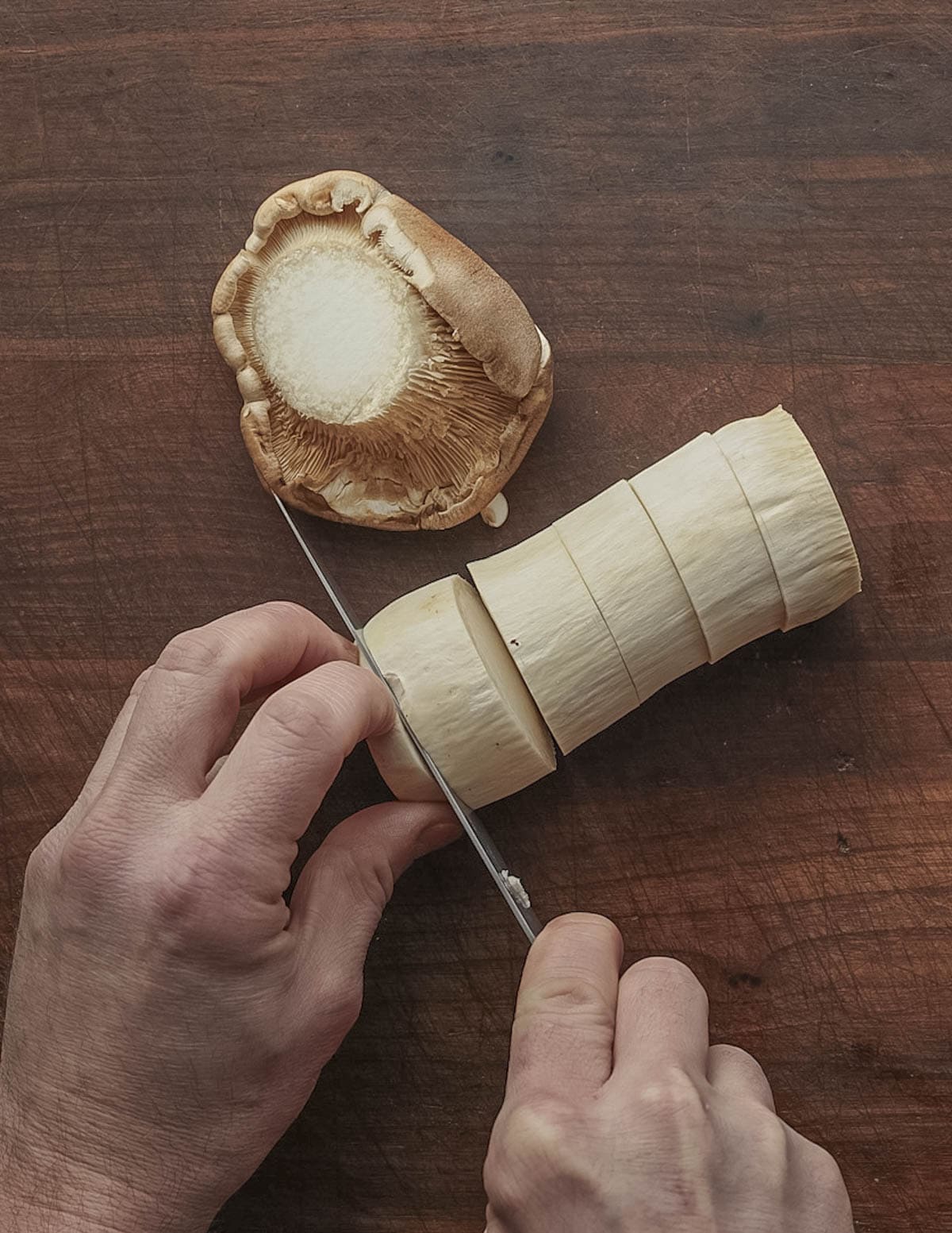 Slicing king oyster or king trumpet mushrooms into thick pieces to make mushroom scallops. 