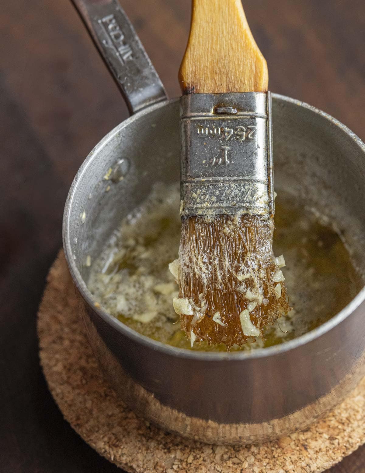 A small pan of ghee or clarified butter and chopped garlic with a brush in it for brushing flatbreads. 