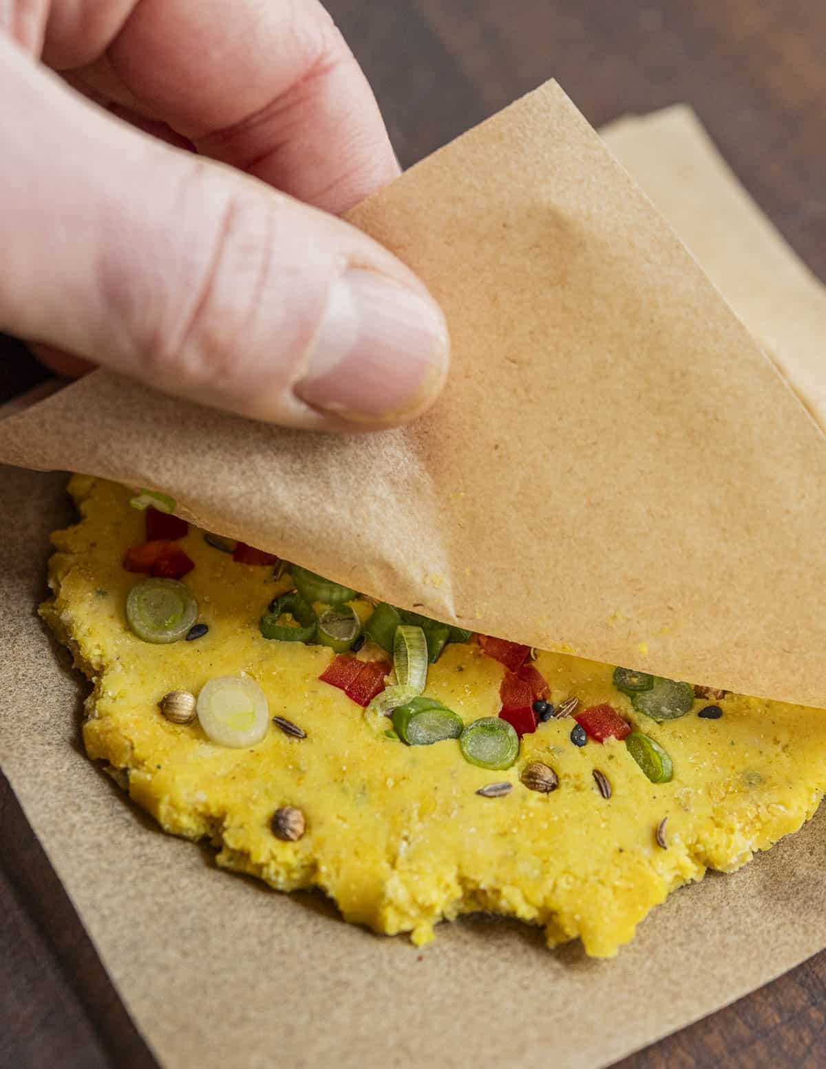 Pressing whole herbs, spices, onions and chili into the dough rounds. 