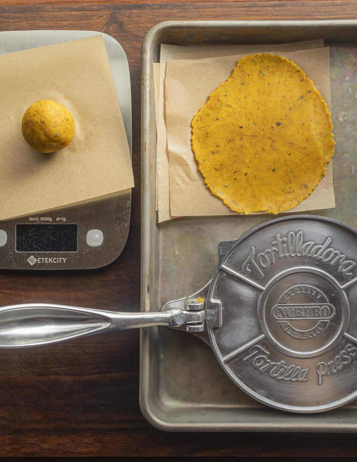 Pressing chickpea dough with a tortilla press. 