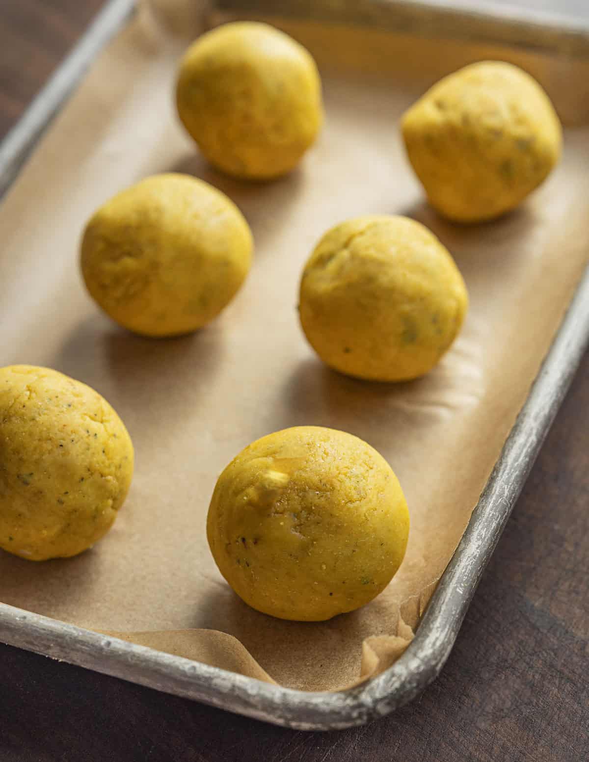 Six balls of missi roti flatbread dough on a baking sheet. 