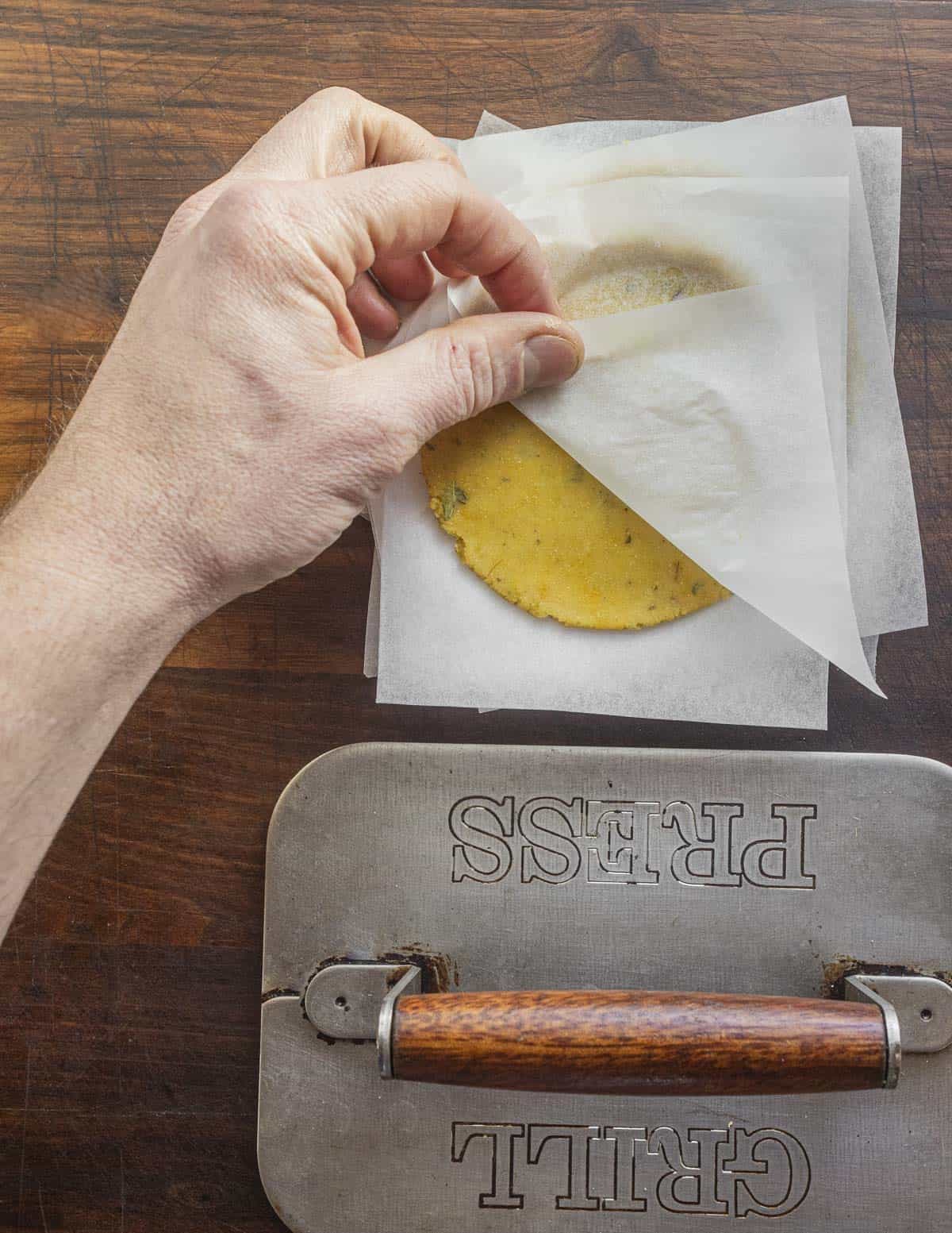 Pressing missi roti dough with a grill press to flatten them. 