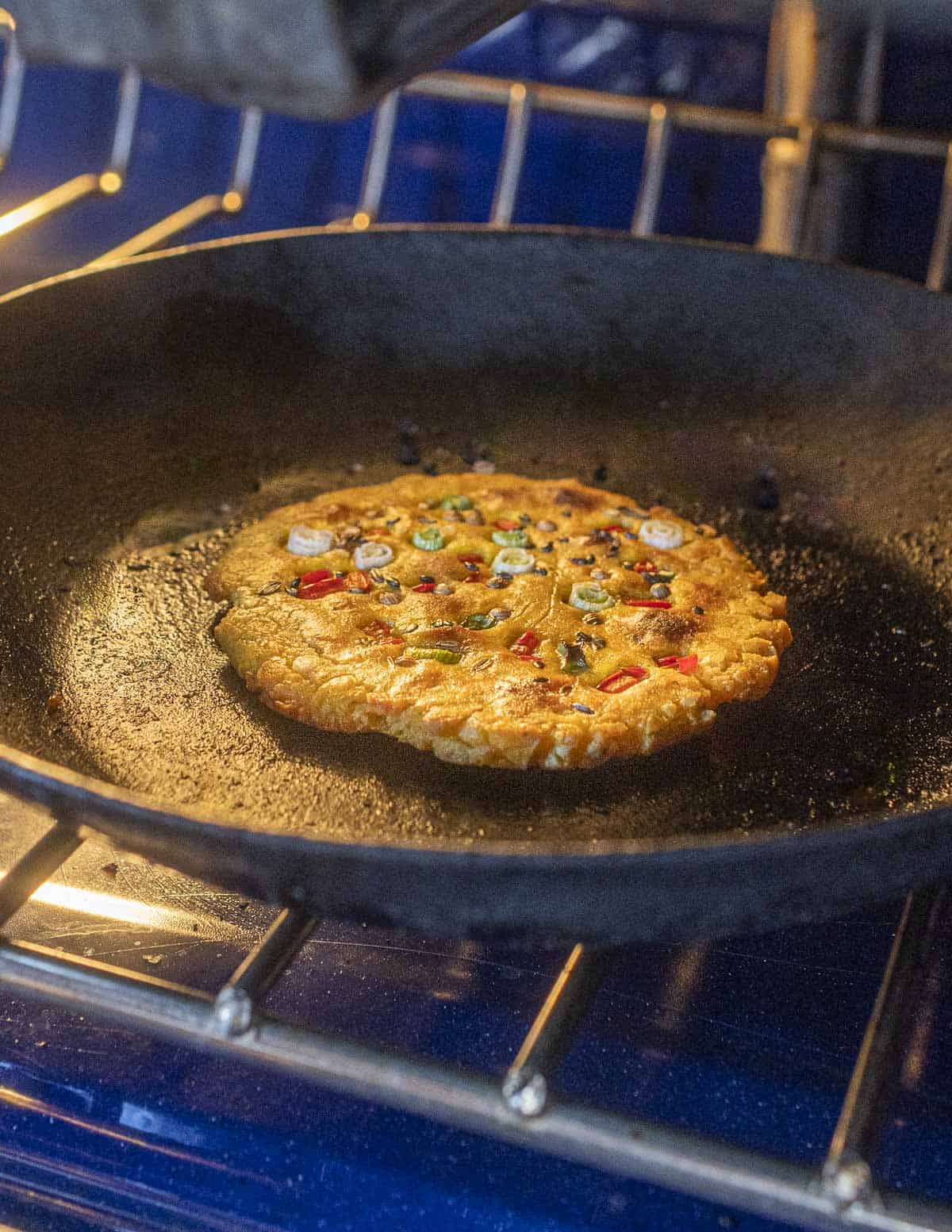 Cooking a missi roti flatbread in a pan under the broiler.