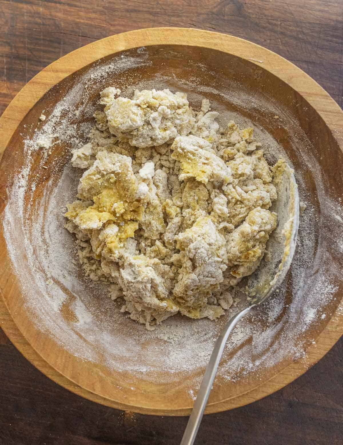 Kneading chickpea flatbread dough in a bowl. 