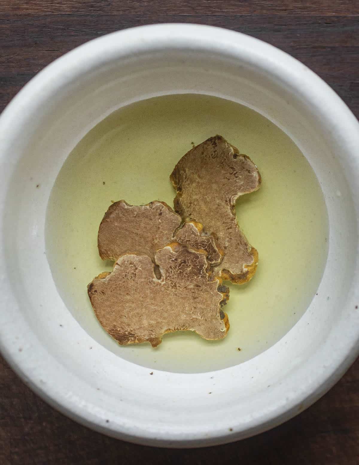 Sliced white truffles in grapeseed oil in a small bowl.