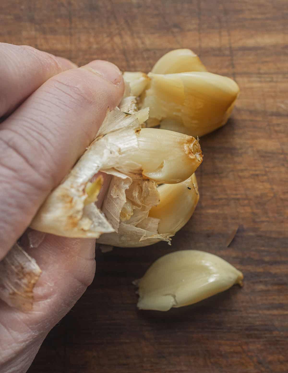 Squeezing roasted garlic cloves from a bulb of roasted garlic. 