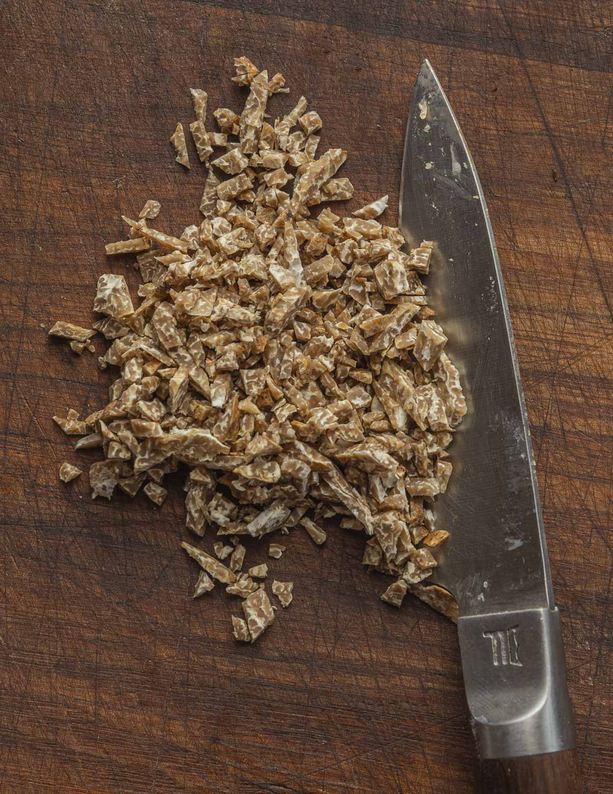 Finely chopped fresh bianchetto truffles next to a knife. 