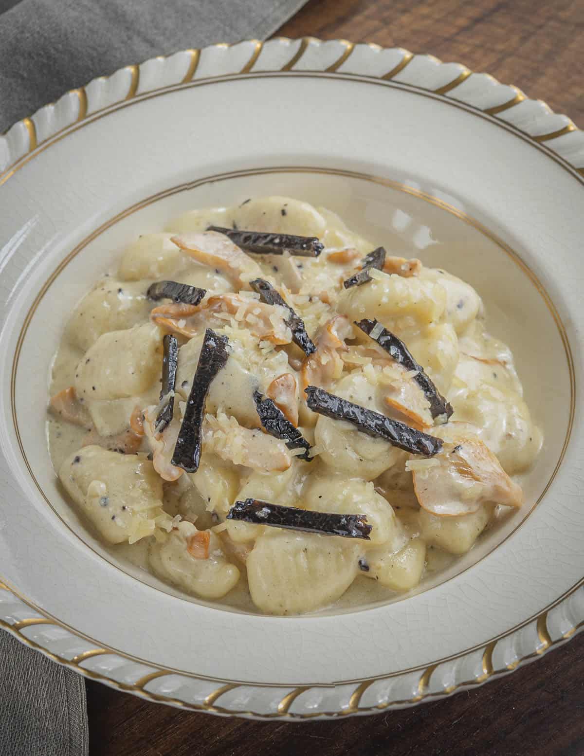 A bowl of potato gnocchi with cream, mushrooms and black truffle. 