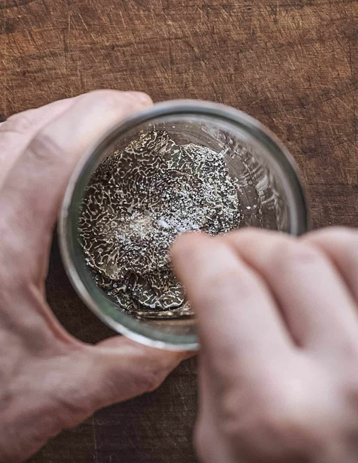 Seasoning truffle slices in a jar with salt.