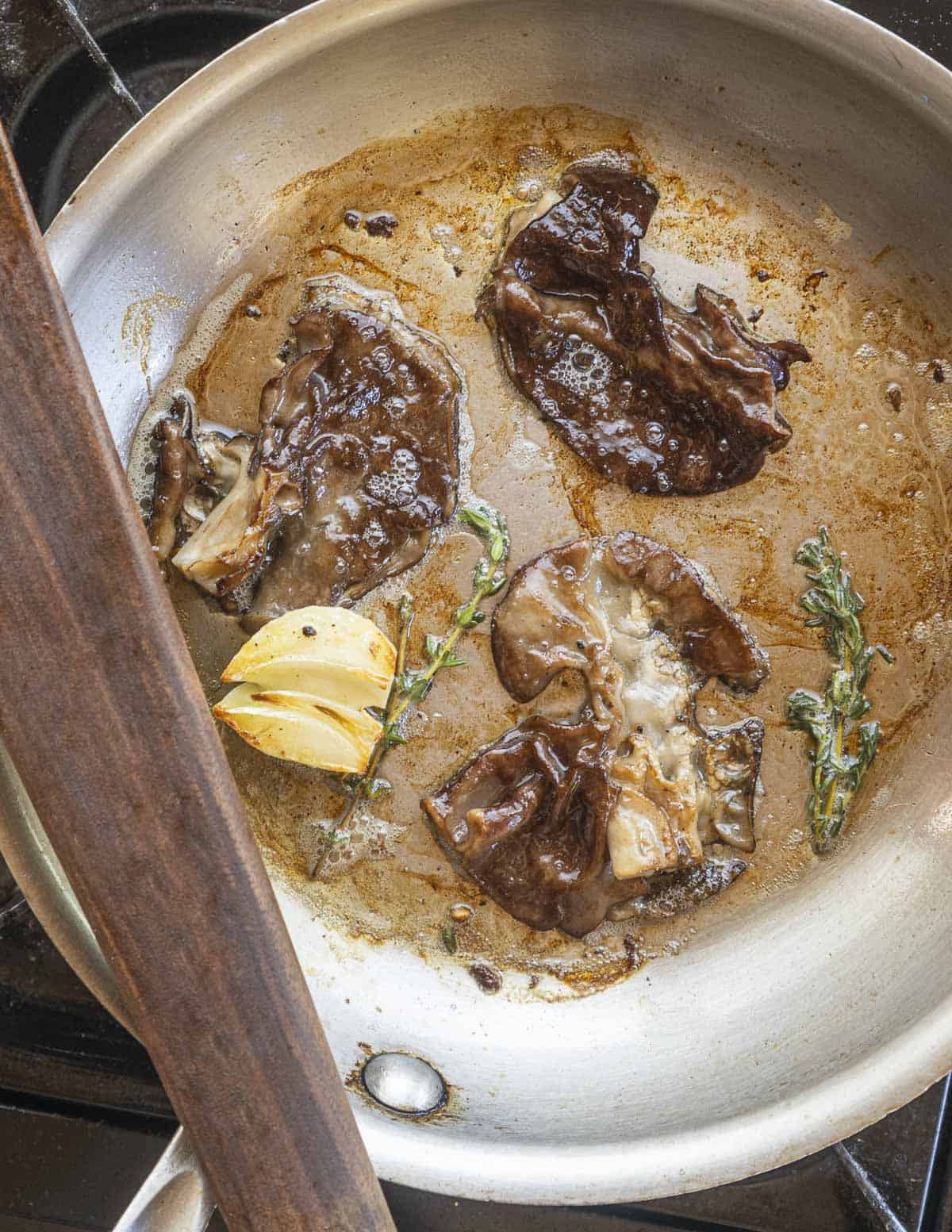 Cooking gyromitra brunnea or elephant ear mushrooms in a pan with garlic and herbs. 