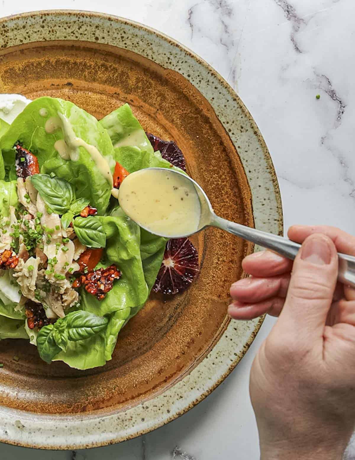 Spooning extra vinaigrette over a butter lettuce salad. 