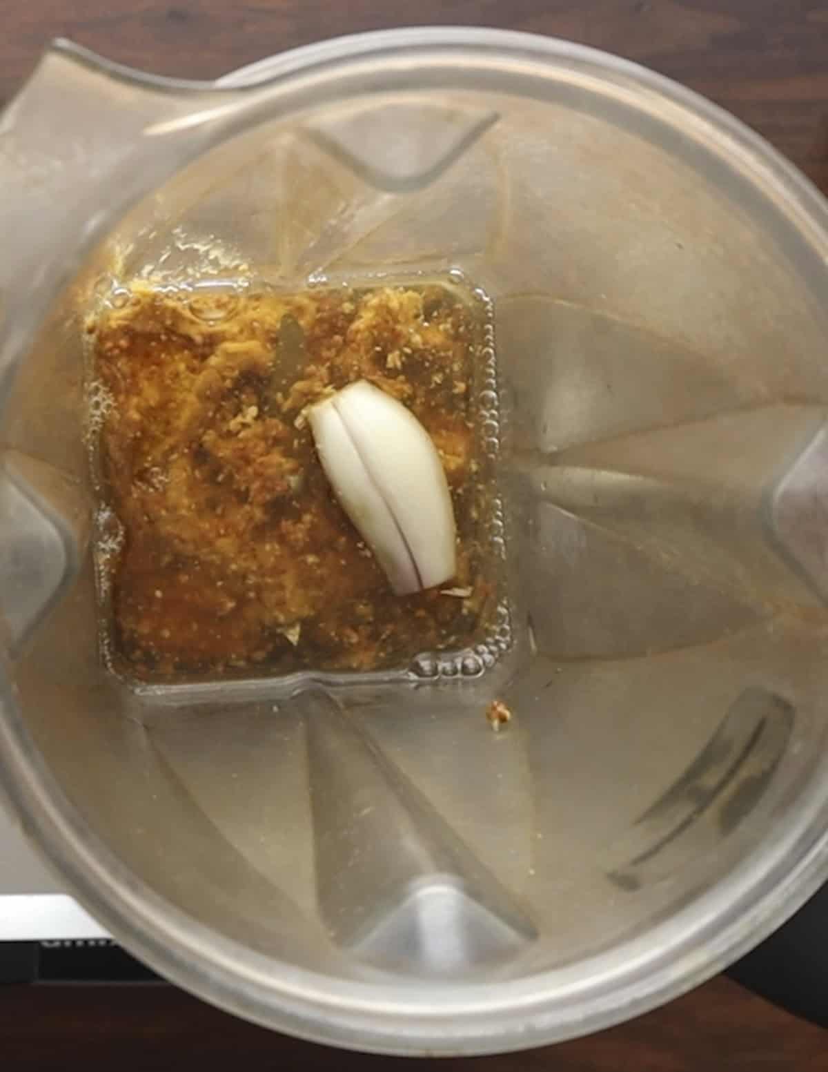 A shallot, maple syrup, and dijon in a blender. 