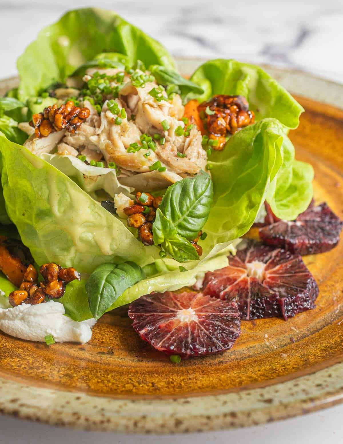 A large lunch salad with roast chicken, basil, chives, candied black walnuts, roasted carrots, blood oranges and chevre.
